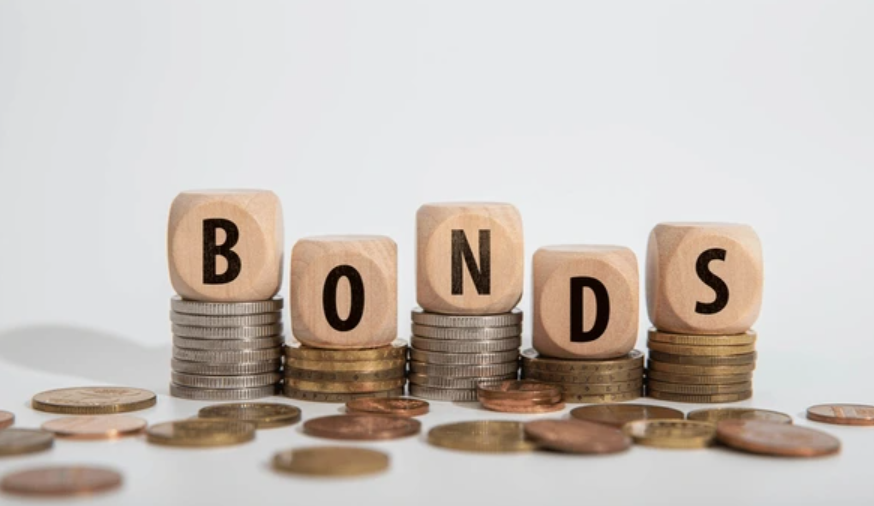 BONDS spelled out with wooden blocks on stacks of coins, representing bond investments and financial strategies.