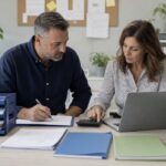 Business owner and bookkeeper coordinating payable and receivable records